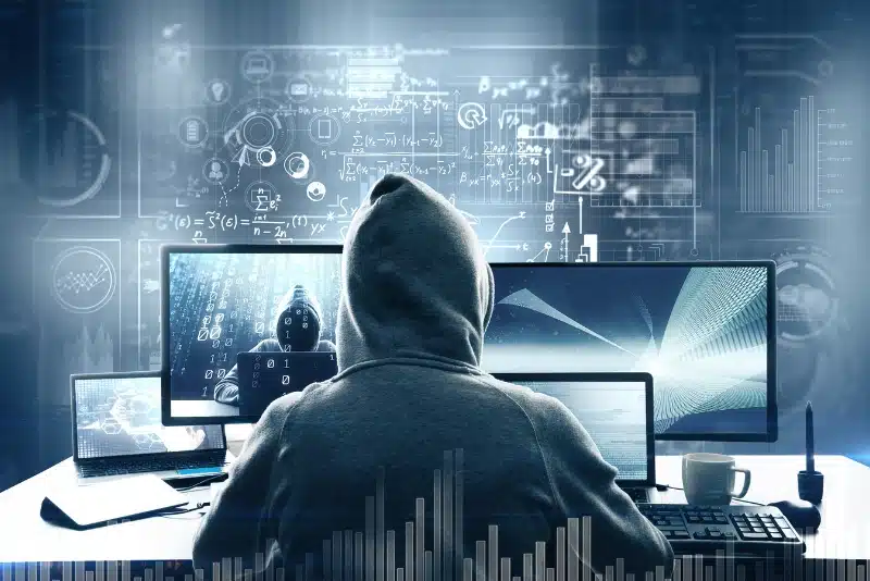 Hooded figure at multi-monitor workstation symbolizing unauthorized data harvesting, AI content scraping, and digital surveillance threatening magazine publishers' rights and content ownership.