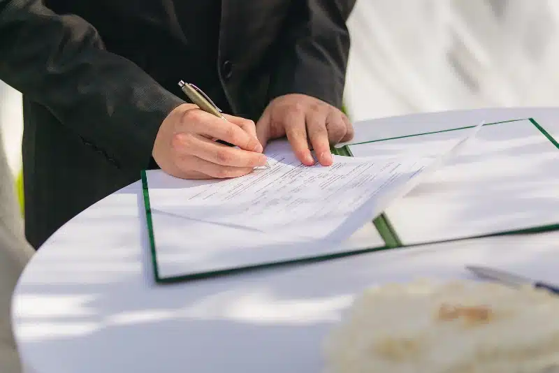 Close-up of a person signing a formal document on a round table, symbolizing content licensing or publishing agreement.