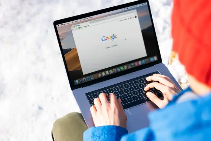 Person using a laptop outdoors in the snow with the Google homepage open, representing Google search, AI overviews, and changing SEO trends in 2025.
