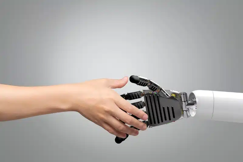 Human hand shaking a robotic AI hand symbolizing the future of journalism and artificial intelligence in 2025.